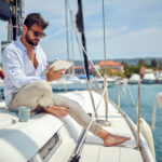 Skupina ľudí na plachetnici počas plavby po mori, ilustruje cenovo dostupnú dovolenku zdieľaním nákladov.