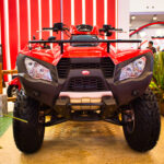 Začiatočník stojí pri štvorkolke a zvažuje jej výber, pripravuje sa na svoju prvú jazdu v teréne.